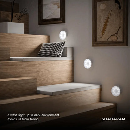 Multiple cool white motion sensor LED lights mounted along a wooden staircase wall for step safety.